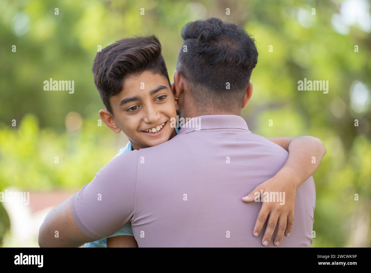 Cheerful indian son hugging or embracing to father at park - concept of relationship, fatherhood and affection Stock Photo