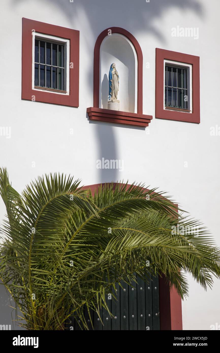 Spain, Andalusia, Moron de la Frontera, hacienda las Alcabalas, virgin placed in a niche and palm tree on the white facade of a Sevillian-style hacienda Stock Photo