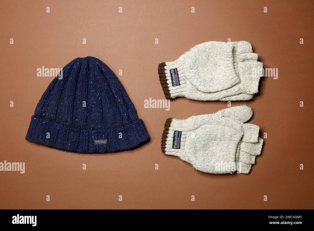 top view on a brown backgorund of a blue warm wool beanie and gloves, studio shot Stock Photo