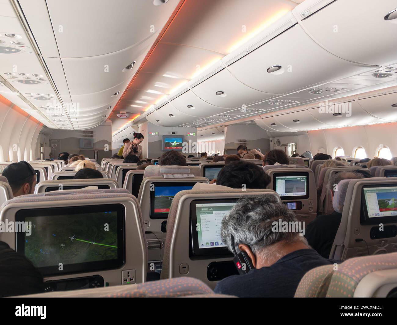 PERTH, AUSTRALIA - JULY 17, 2018: Interior of Emirates airlines aircraft on long haul flight, stewardess delivering  headphones Stock Photo