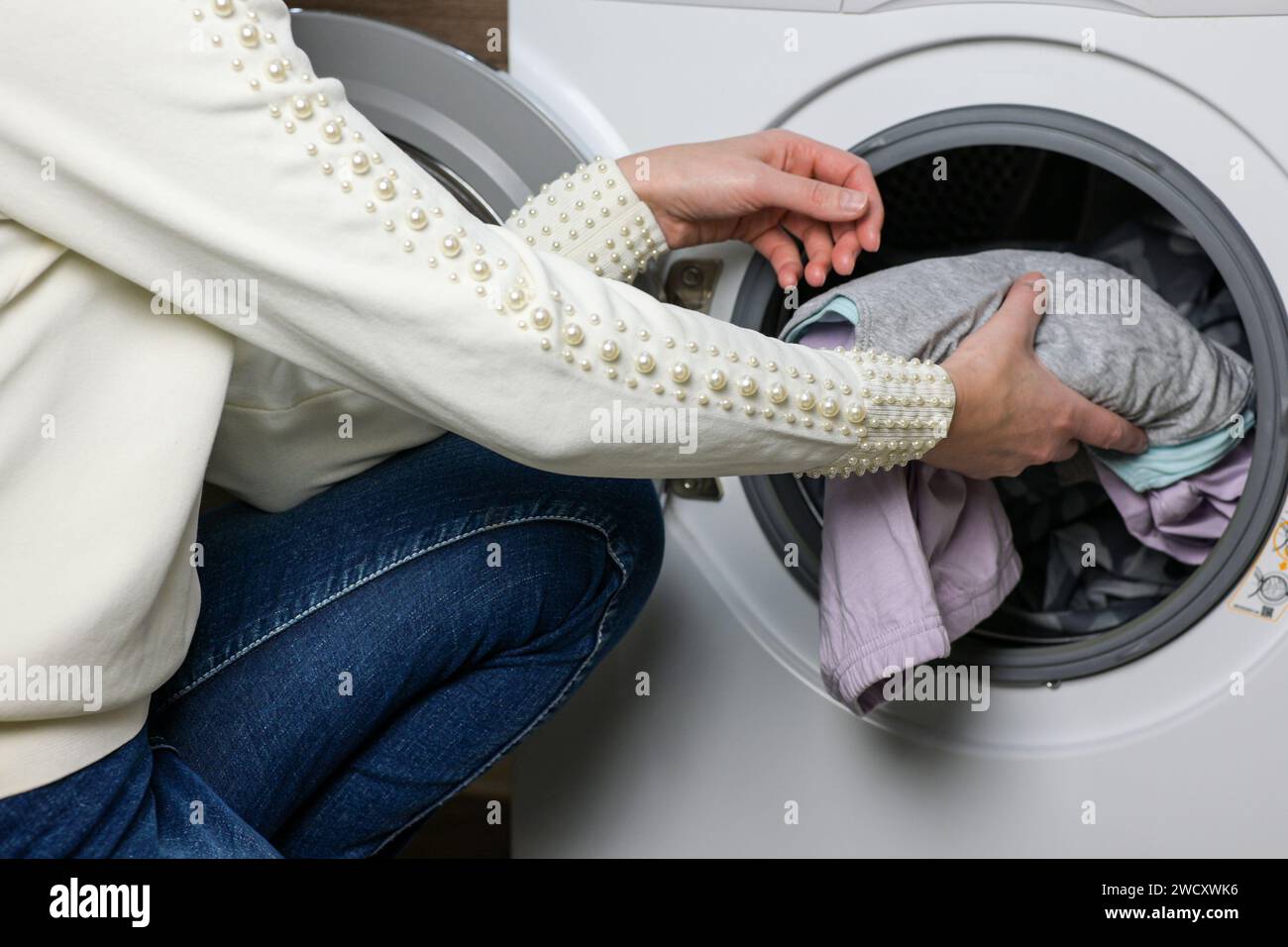 mom puts the baby's clothes in the washing machine Stock Photo Alamy
