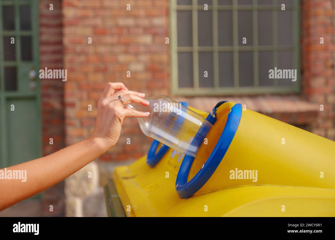 woman throwing plastic bottle Recycling bin stand on european street