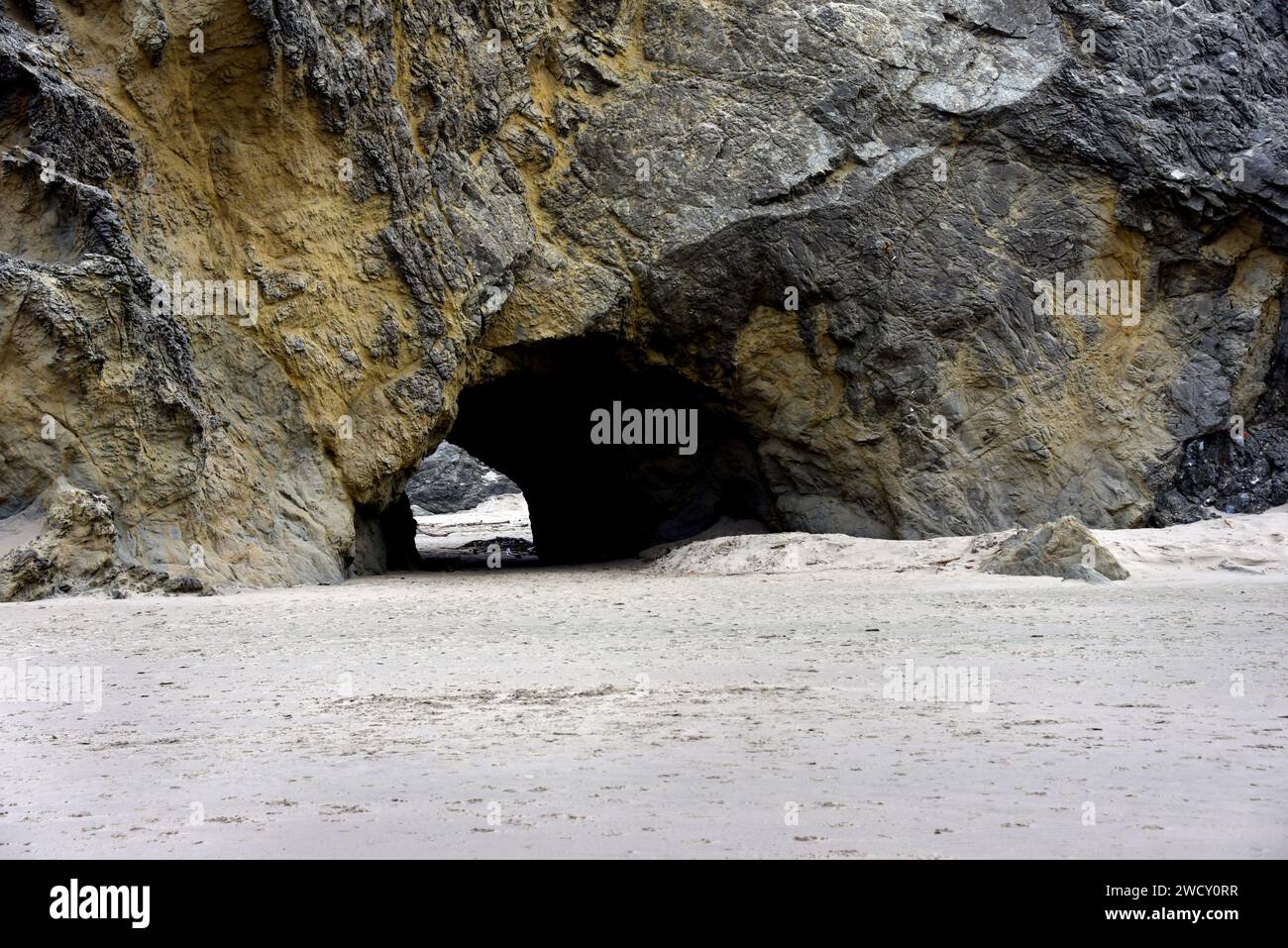 Huge rocks hide small sea cave on Bandon Beach in Oregon. Stock Photo