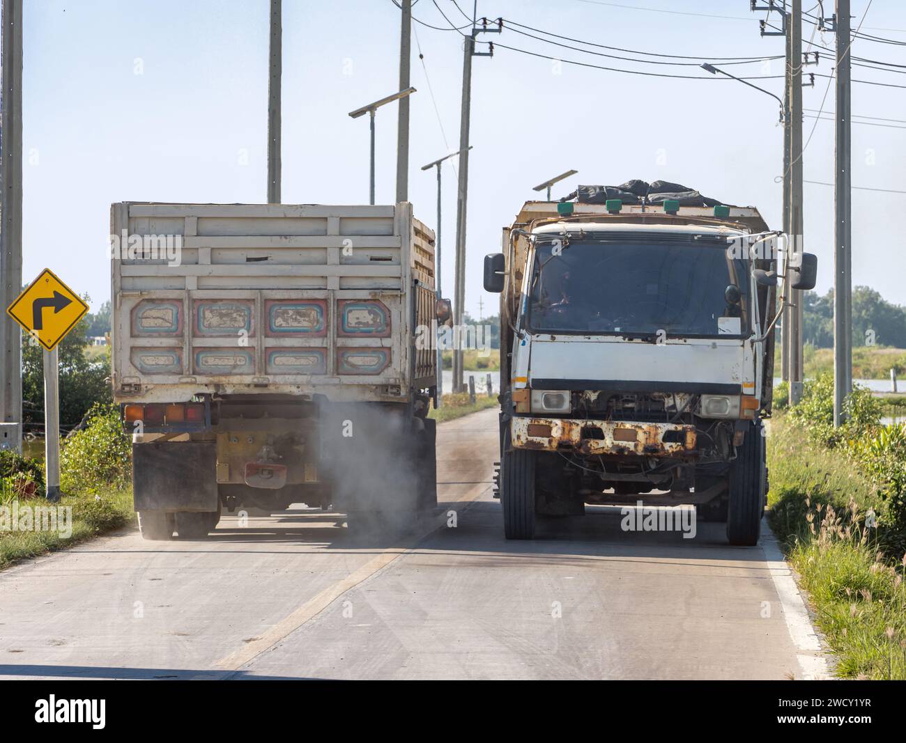 Two trucks pass close by on a country road, Thailand Stock Photo