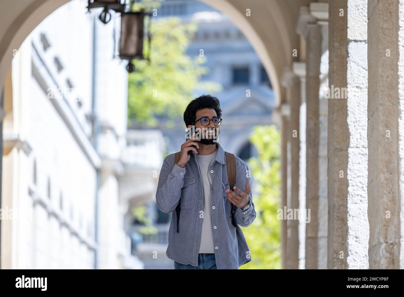Dark-haired man walking through the arch and talking on the phone Stock Photo