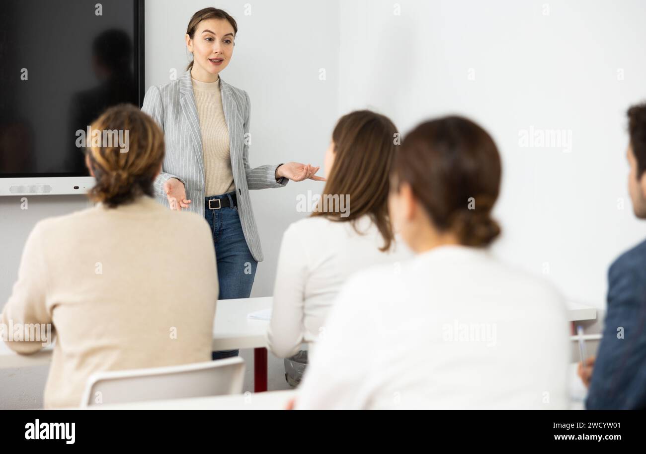 Young female teacher giving lecture to group of student Stock Photo