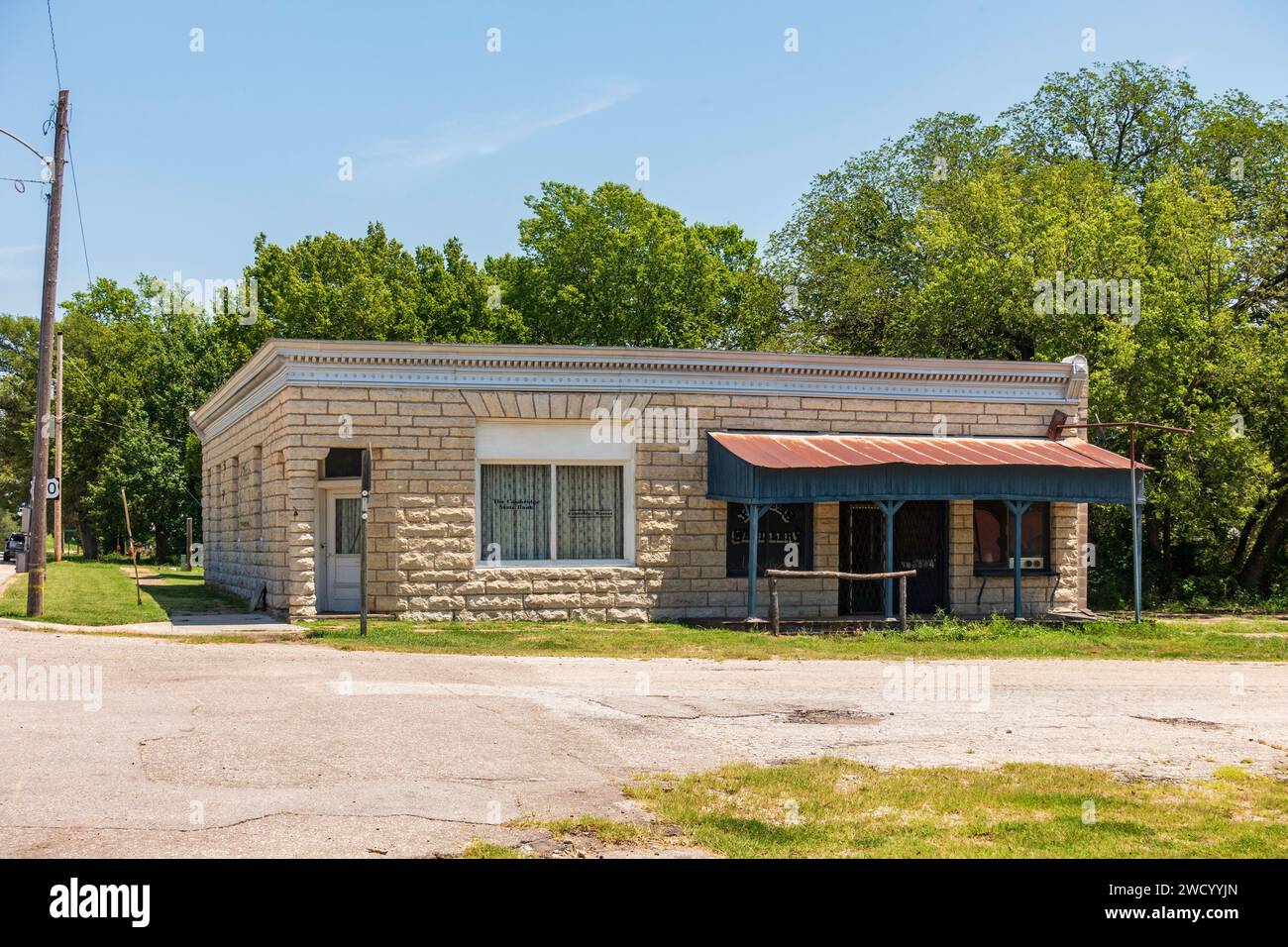 A saddlery business made of sandstone bricks with a rusty tin porch roof and a hitching post in Burden, Kansas, USA. Population 535. Stock Photo