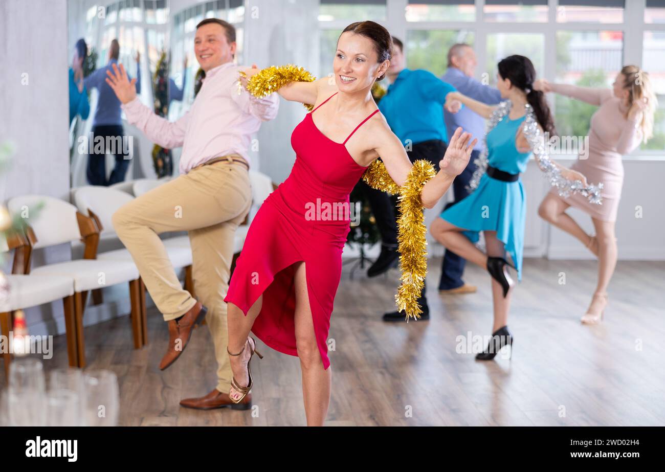 Happy brunette dancing jive with male partner during New Year party Stock Photo