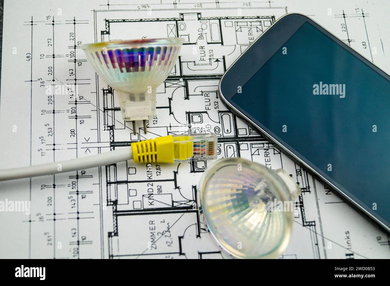 reflector lamps, network cable and smartphone on construction drawing, symbolic image for Smart Home Stock Photo