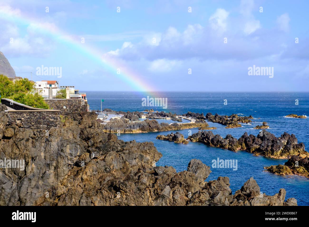 Natural lava swimming pools seascape, rainbow over Porto Moniz ocean tidal swimming pool, sea pool, North rocky coast of Madeira Island, Portugal Stock Photo