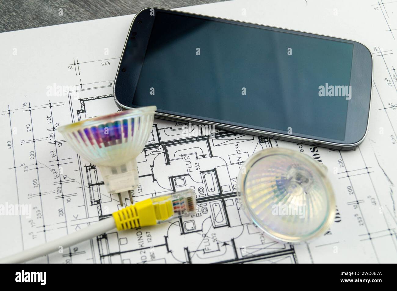 reflector lamps, network cable and smartphone on construction drawing, symbolic image for Smart Home Stock Photo