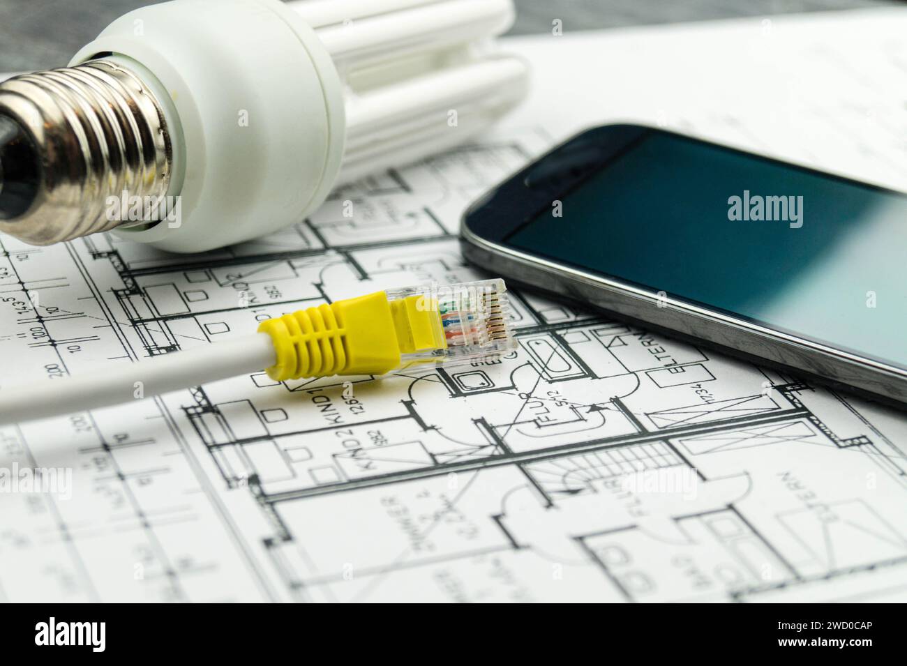 Energy-saving lamp, smart phone and network plug on construction drawings, symbolic image for smart home Stock Photo