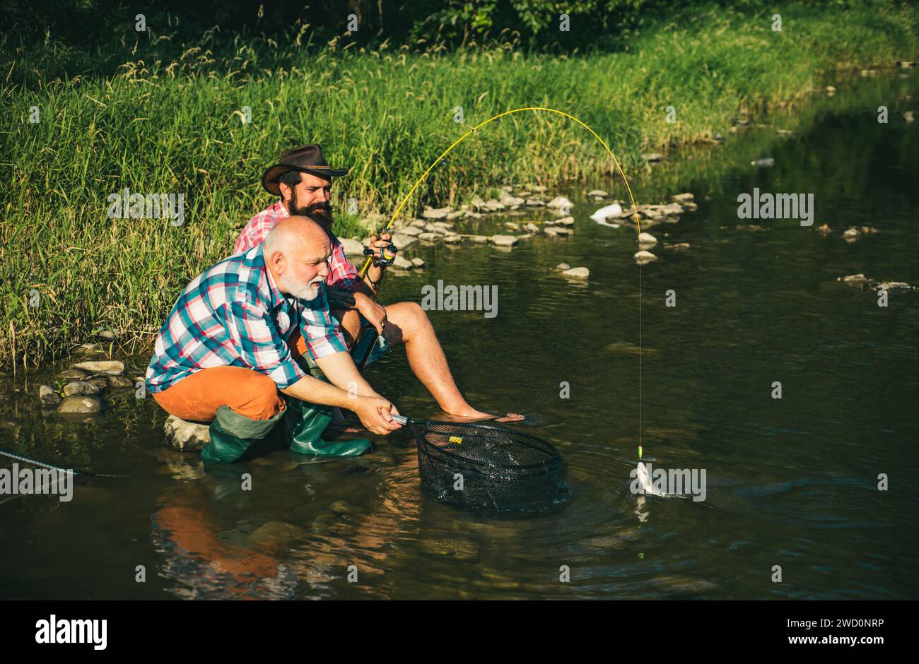 Two men friends fisherman fishing on river. Old father and son with rod ...