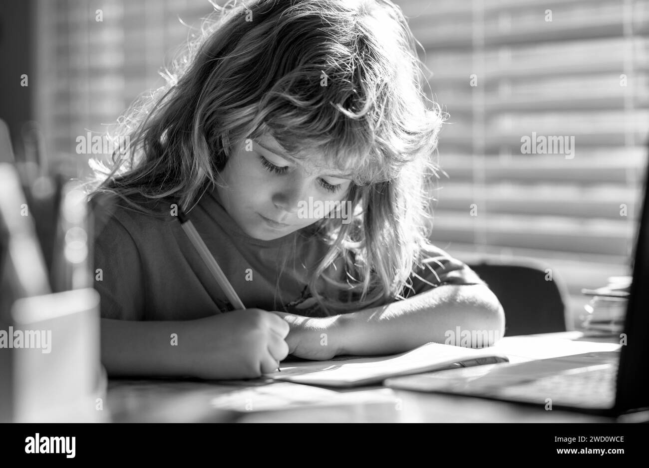 Child writing at school. Funny child girl doing homework writing and reading at home. Little student at desk in school classroom. Stock Photo