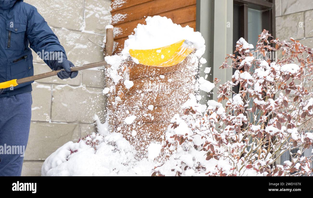 Man shoveling snow off of his driveway after a winter storm in Canada. Man with snow shovel cleans sidewalks in winter. Winter time. Stock Photo