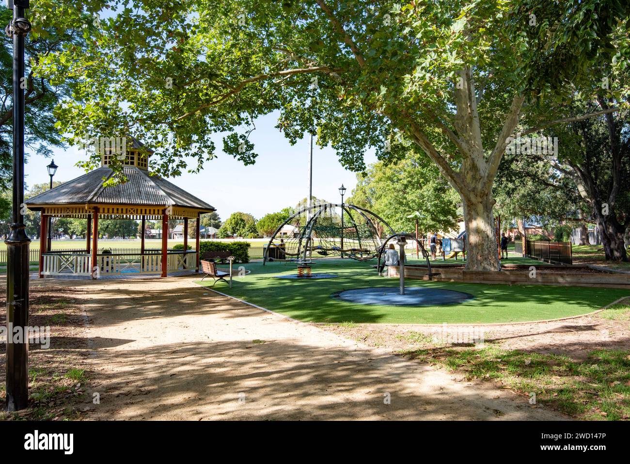 A rotunda and childrens playground are shaded by large oak trees bounding a cricket oval in the outer Sydney suburb of Richmond, NSW, Australia Stock Photo