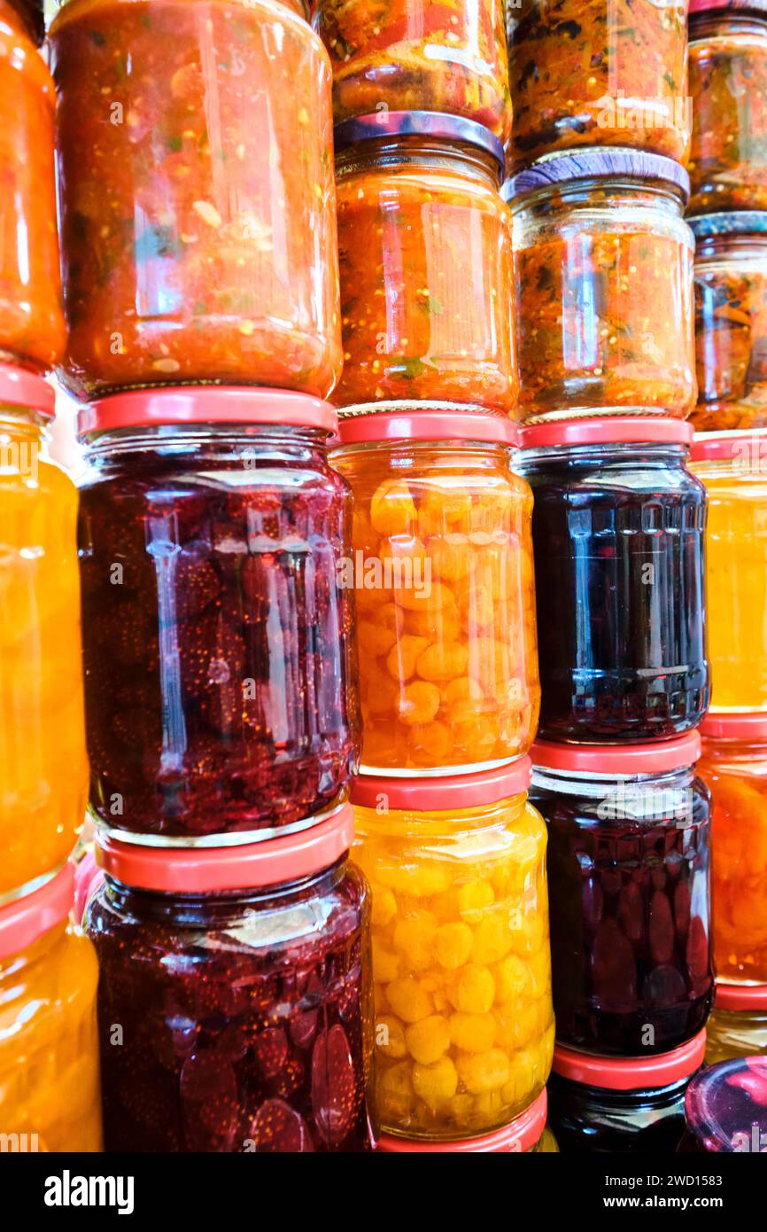Detail view of many stacked jars of canned, homemade sauces, jams, pickled items. At the main local, Soviet era food market, the Green Bazaar. In Alma Stock Photo