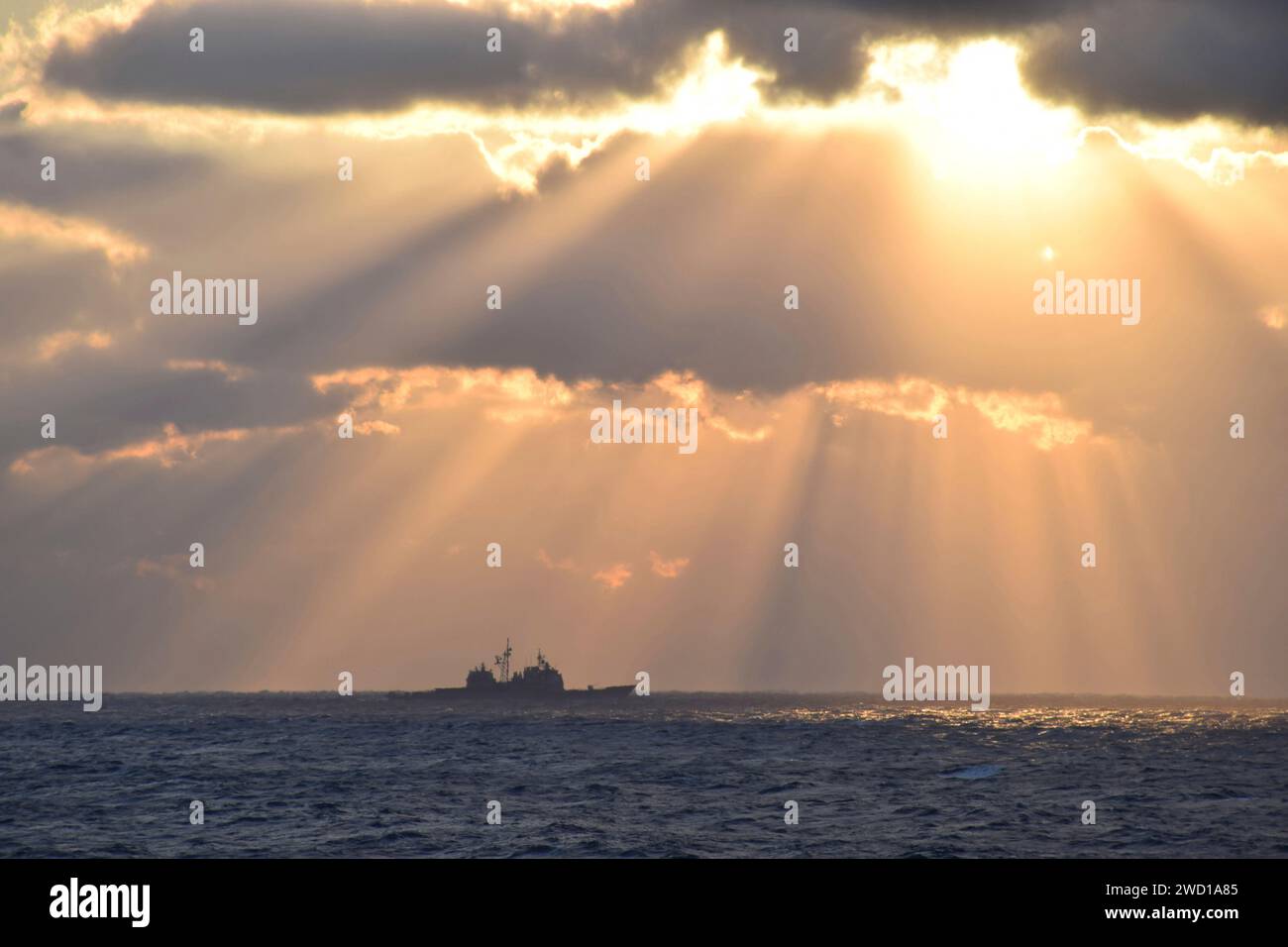 Rays of light shine down on guided-missile cruiser USS Vella Gulf in the Atlantic Ocean. Stock Photo
