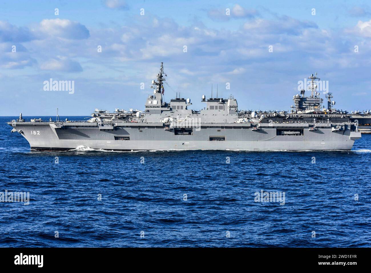 Japanese Navy helicopter destroyer Js Ise transits alongside U.S. Navy aircraft carrier USS Nimitz. Stock Photo
