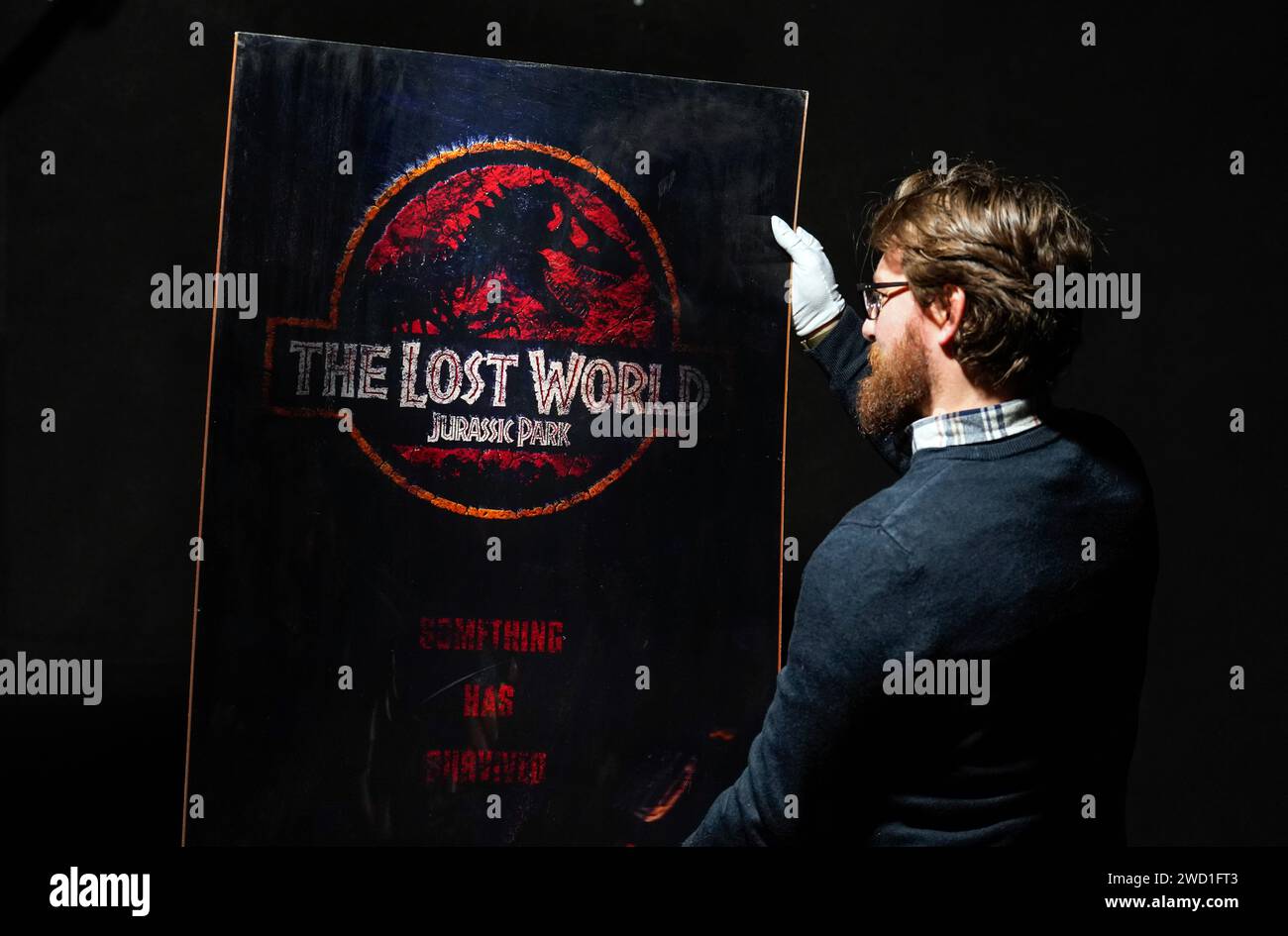 A Propstore employee looks at a special 3D Lenticular for the 1997 film 'The Lost World: Jurassic Park' (estimate £600 - £1,200) during a preview for Propstore's UK poster auction, at the Propstore in Rickmansworth, Hertfordshire. Picture date: Wednesday January 17, 2024. Stock Photo