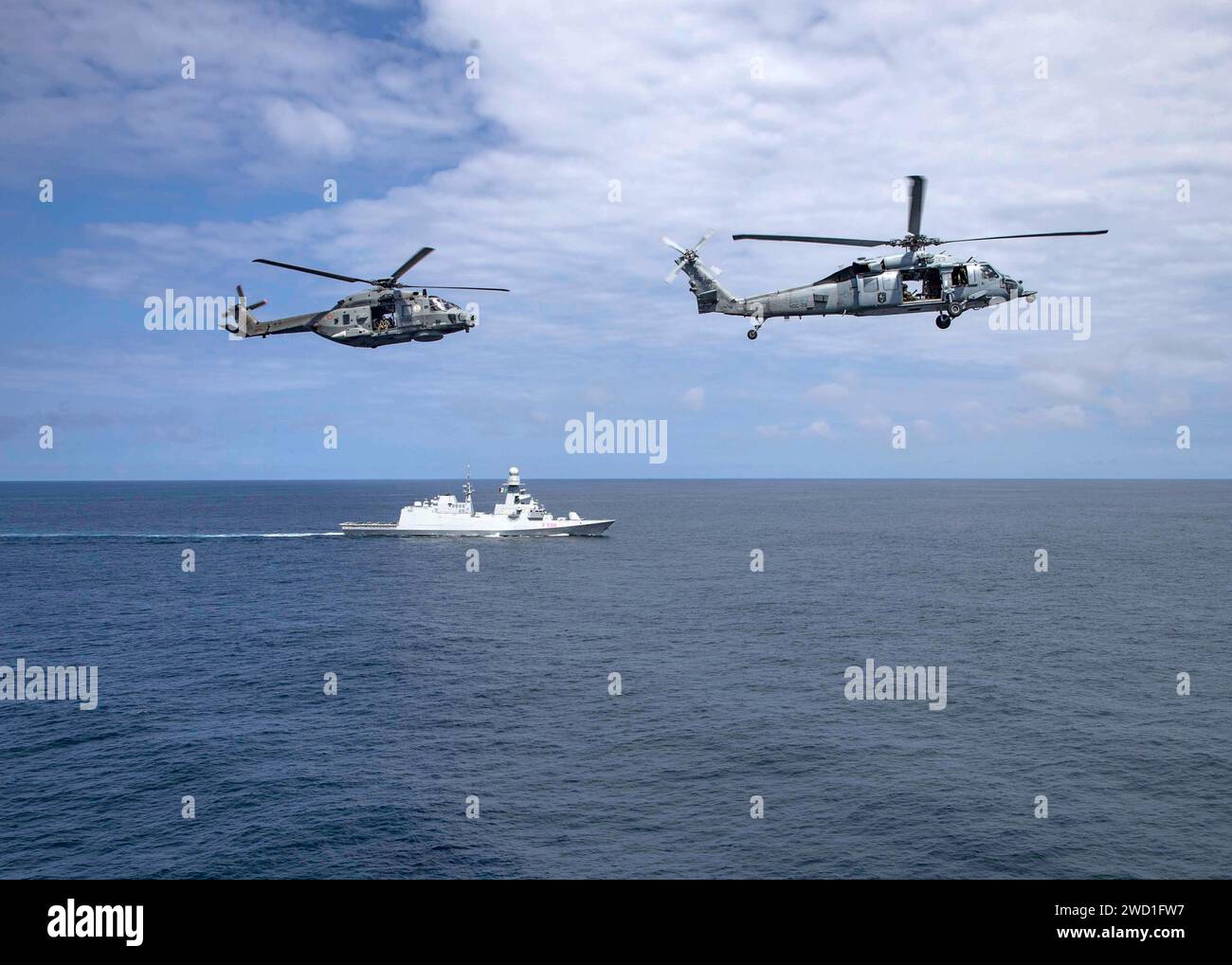 A U.S. Navy MH-60S Seahawk and an Italian NH 90 helicopter execute a flyby over Italian Navy frigate ITS Federico Martinengo. Stock Photo