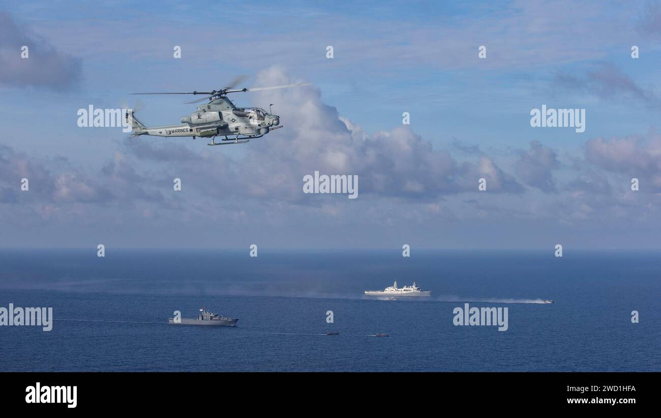 A U.S. Marine Corps AH-1Z Viper helicopter flies above U.S. Navy and Republic of Singapore Navy ships in the South China Sea. Stock Photo