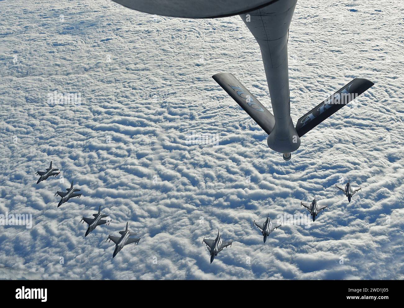 U.S. Air Force F-16C's and Swedish Air Force JAS 39 Gripens fly in formation behind a KC-135 Stratotanker. Stock Photo