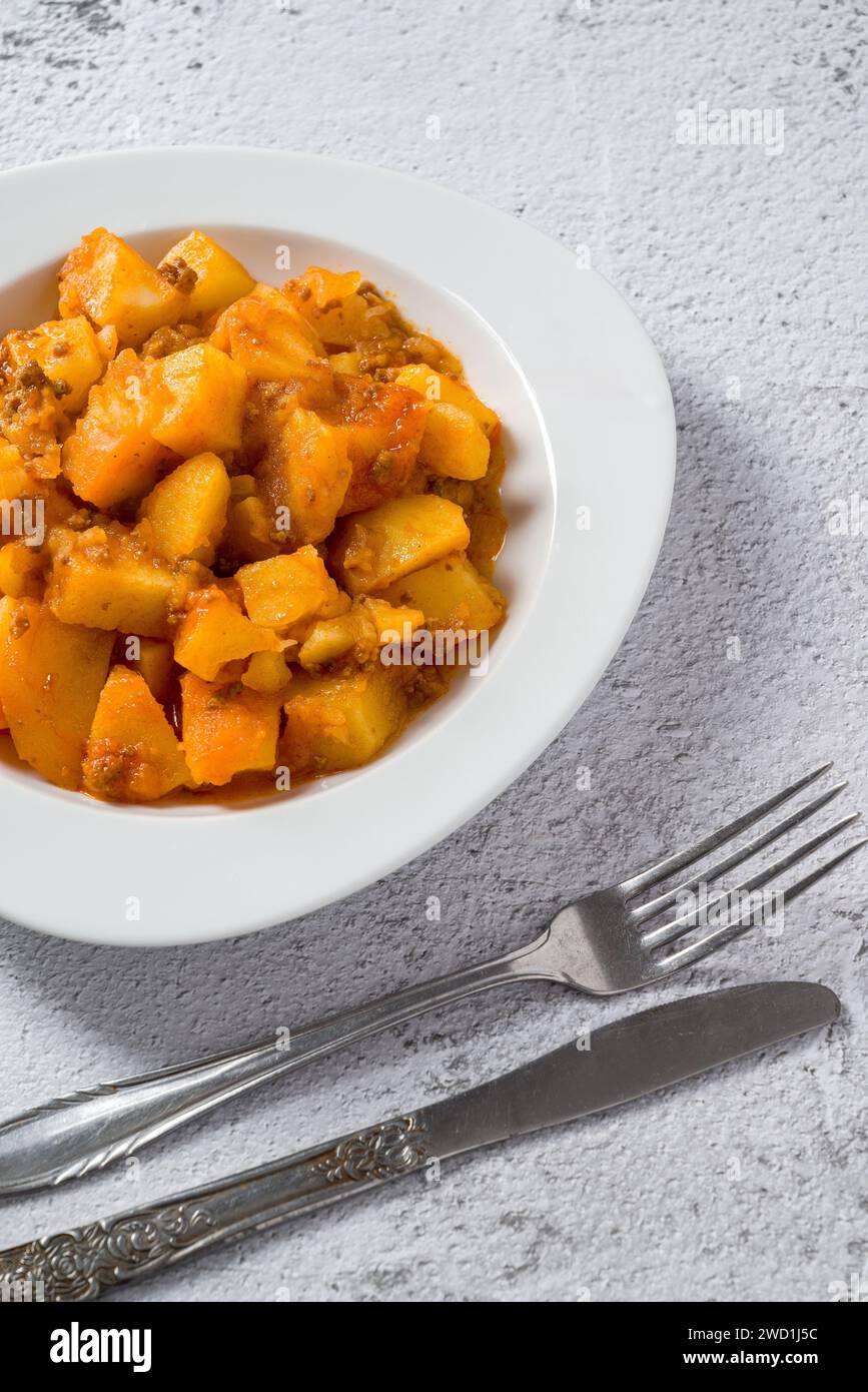 Minced meat and potato dish on white porcelain plate on stone table Stock Photo