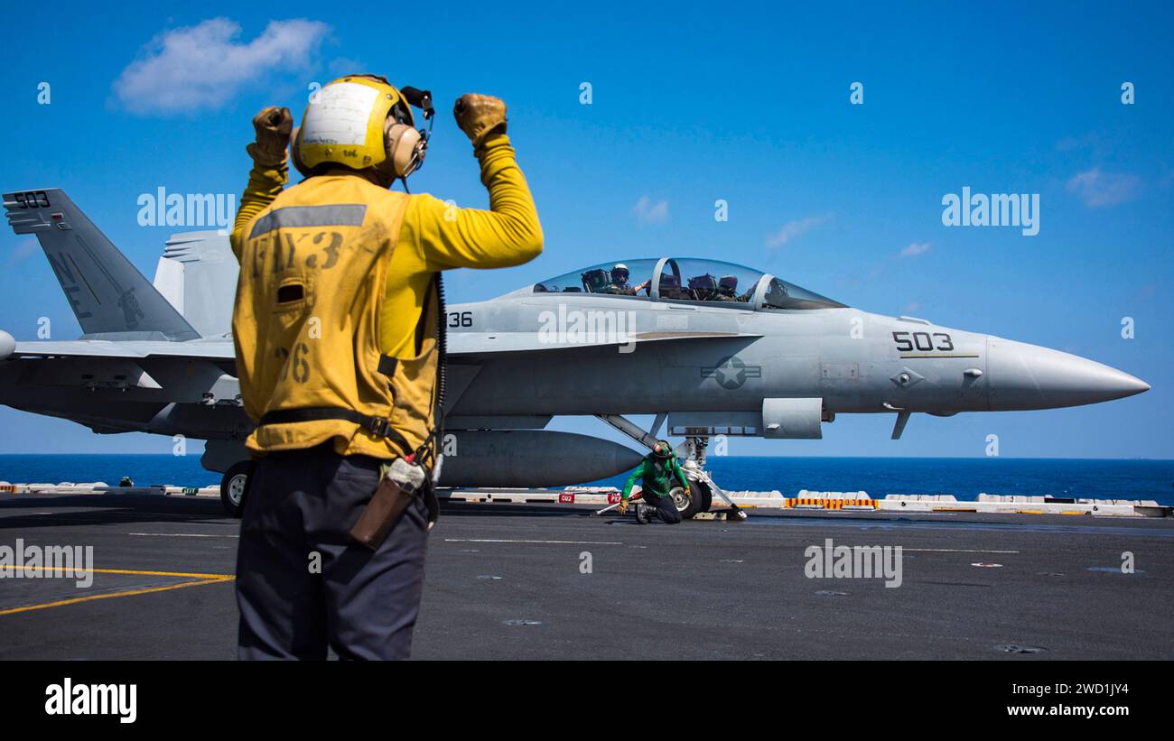 A Sailor assigned to the aircraft carrier USS Carl Vinson directs the crew of an EA-18G Growler. Stock Photo