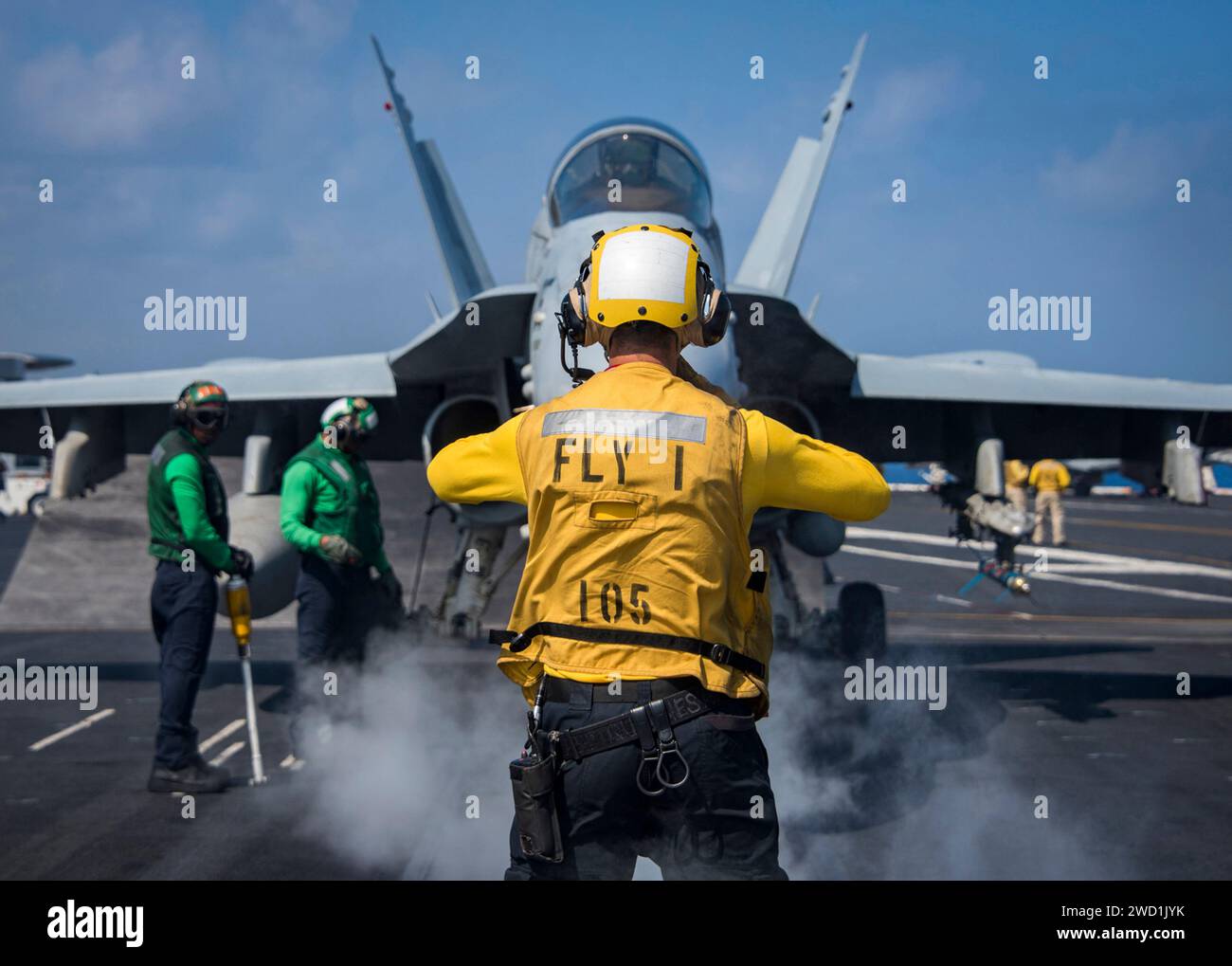 Aviation Boatswain's Mate directs the pilot of an F/A-18C Super Hornet aboard USS Carl Vinson. Stock Photo