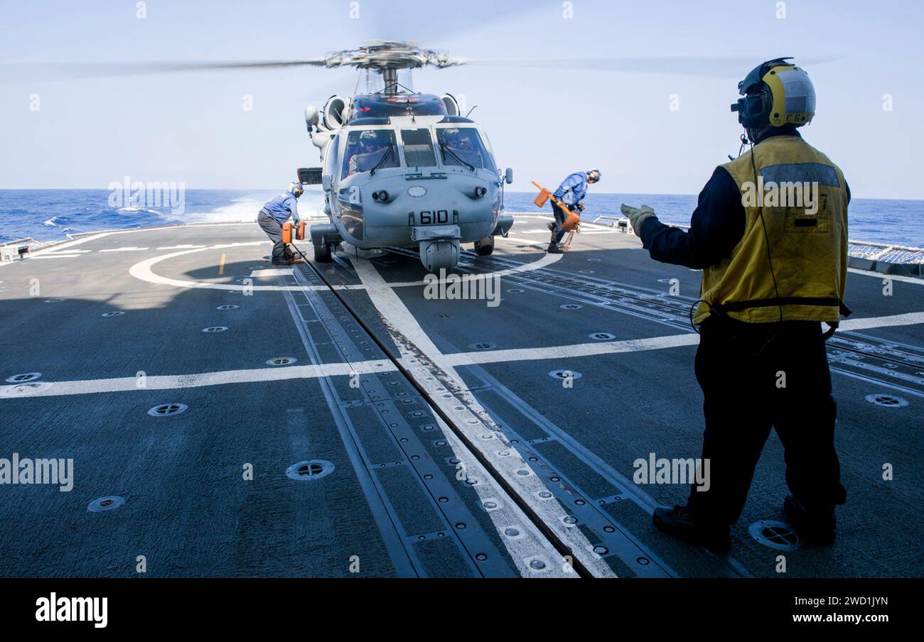 Sailors pull chains off of an MH-60S Sea Hawk helicopter, from the flight deck of  USS Lake Champlain. Stock Photo