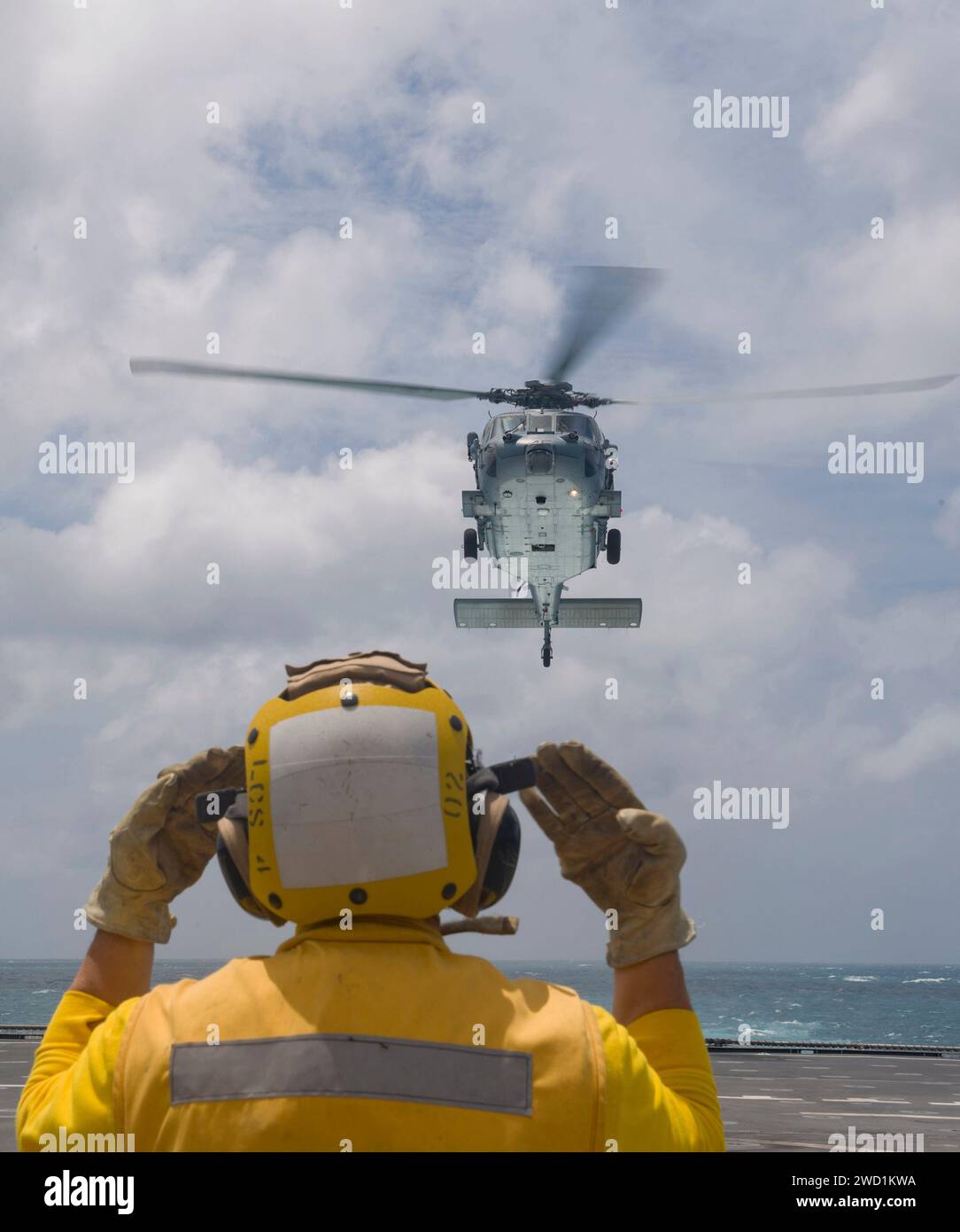 Airman signals an MH-60S Sea Hawk helicopter to land on the flight deck of USS Coronado. Stock Photo
