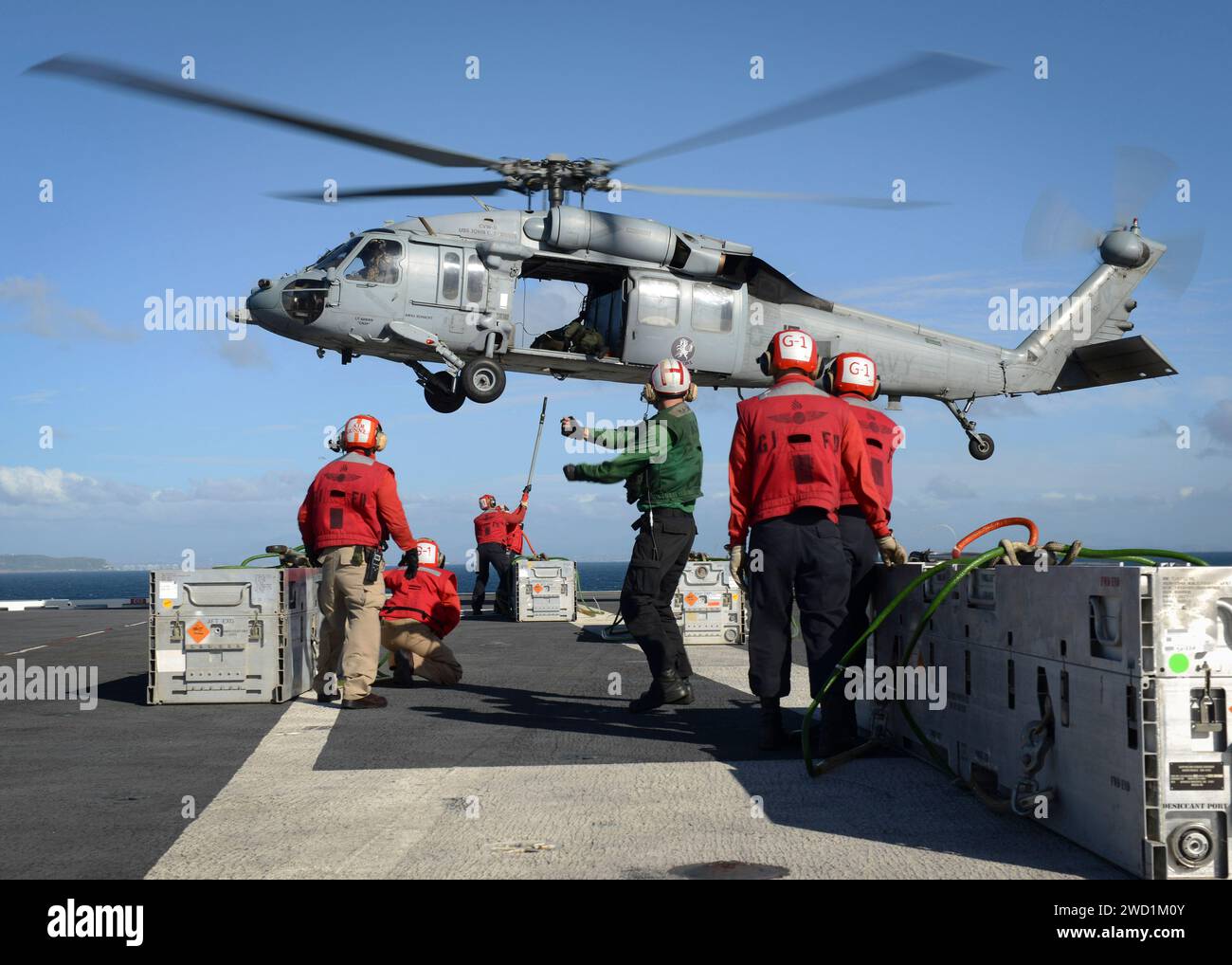 Sailors load ammunition onto an MH-60S Sea Hawk on the flight deck of USS Nimitz. Stock Photo