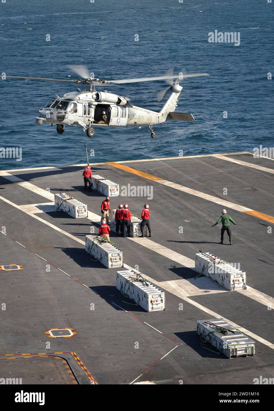 Sailors load ammunition onto an MH-60S Sea Hawk helicopter aboard USS Nimitz. Stock Photo