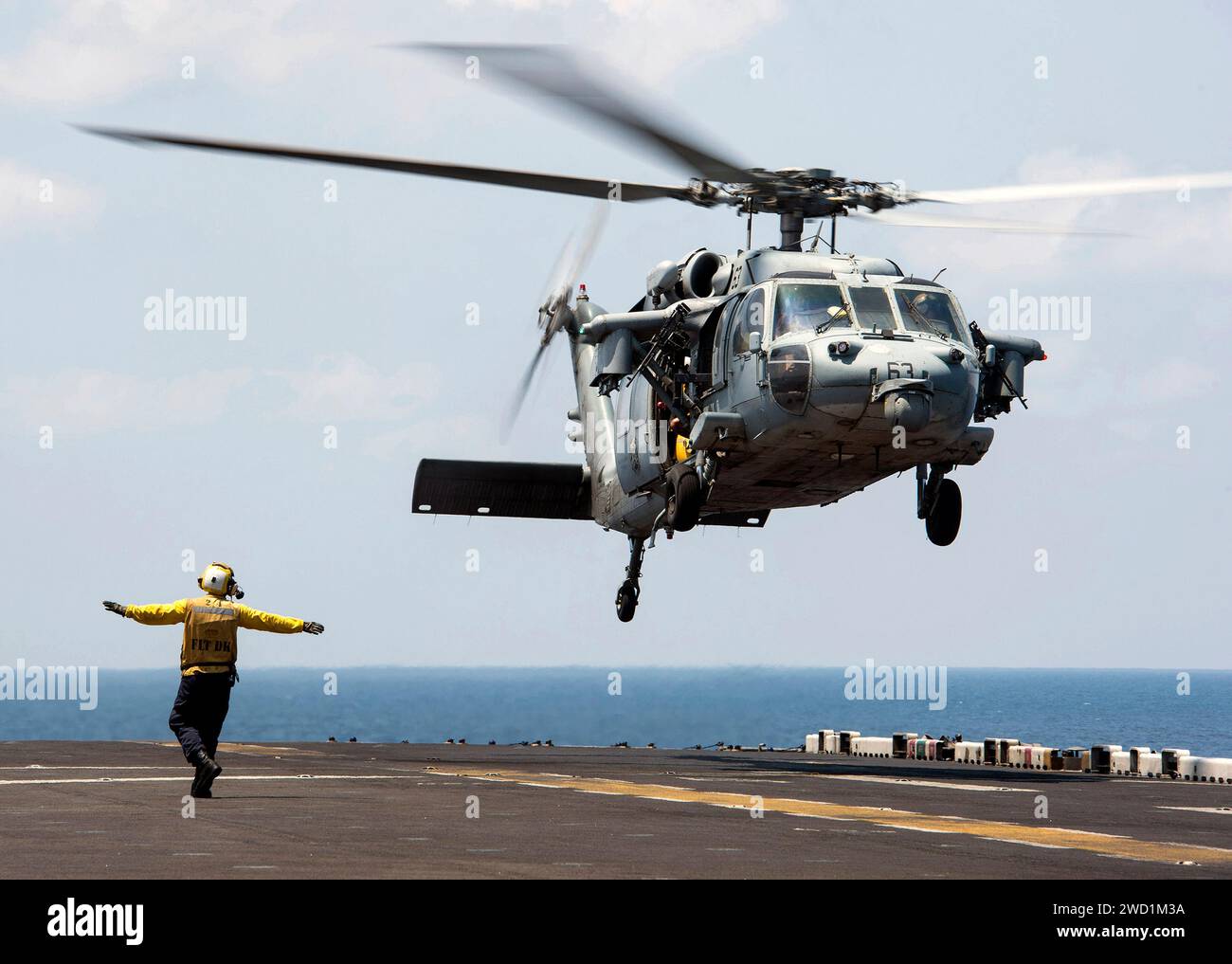 An MH-60S Sea Hawk lands aboard the amphibious assault ship USS Makin Island. Stock Photo