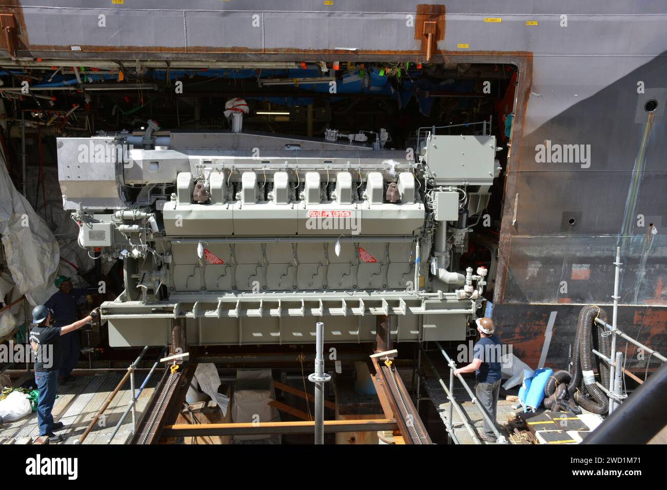 The replacement engine for USS Freedom is moved into position through a precise cut in the side of the hull. Stock Photo