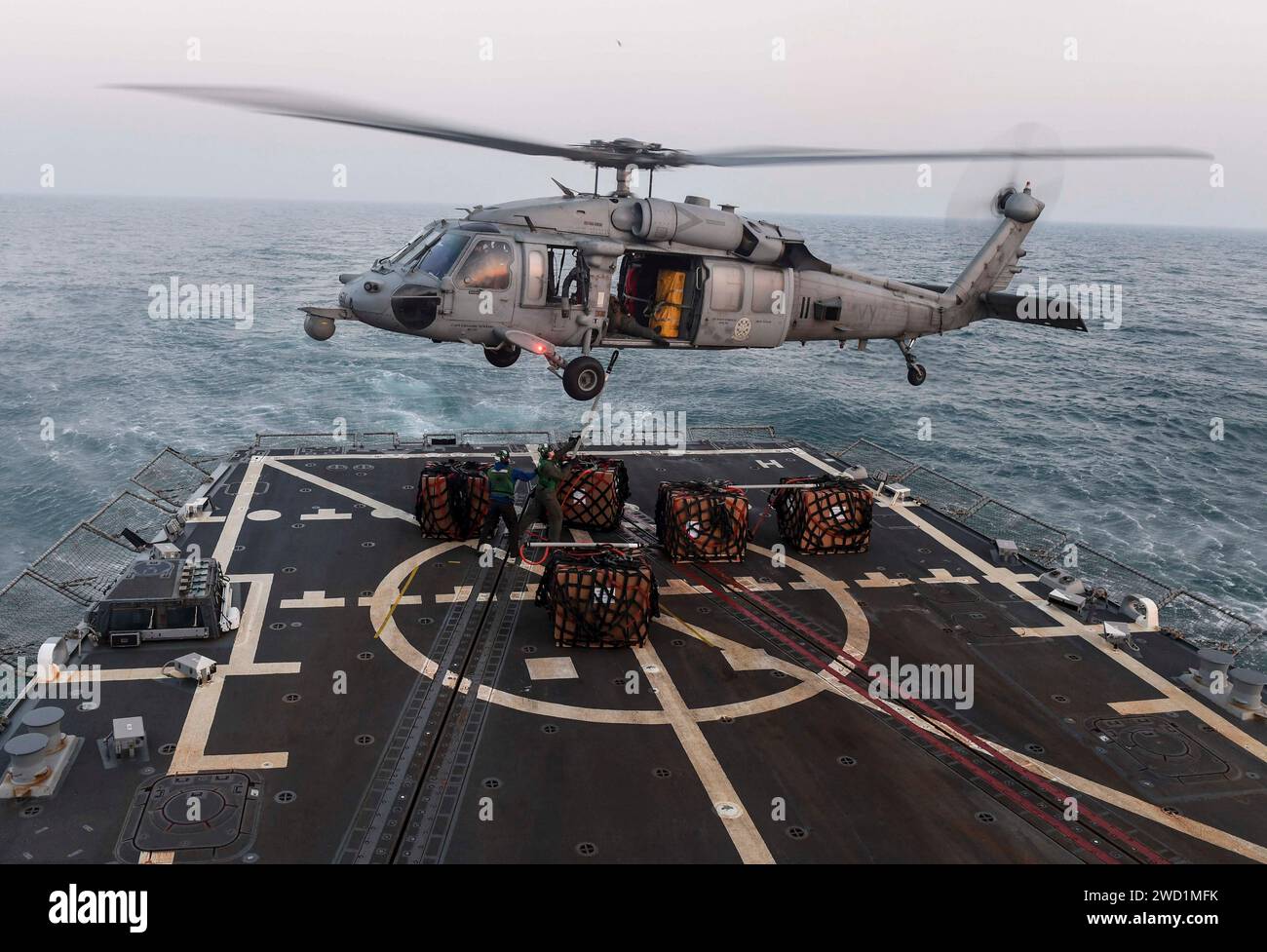Sailors attach the pallet hook to an MH-60S Sea Hawk helicopter aboard USS Wayne E. Meyer. Stock Photo