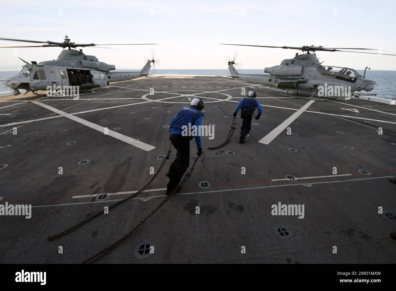 Airmen attach tie down chains to an AH-1Z Viper Attack helicopter aboard USS San Diego. Stock Photo