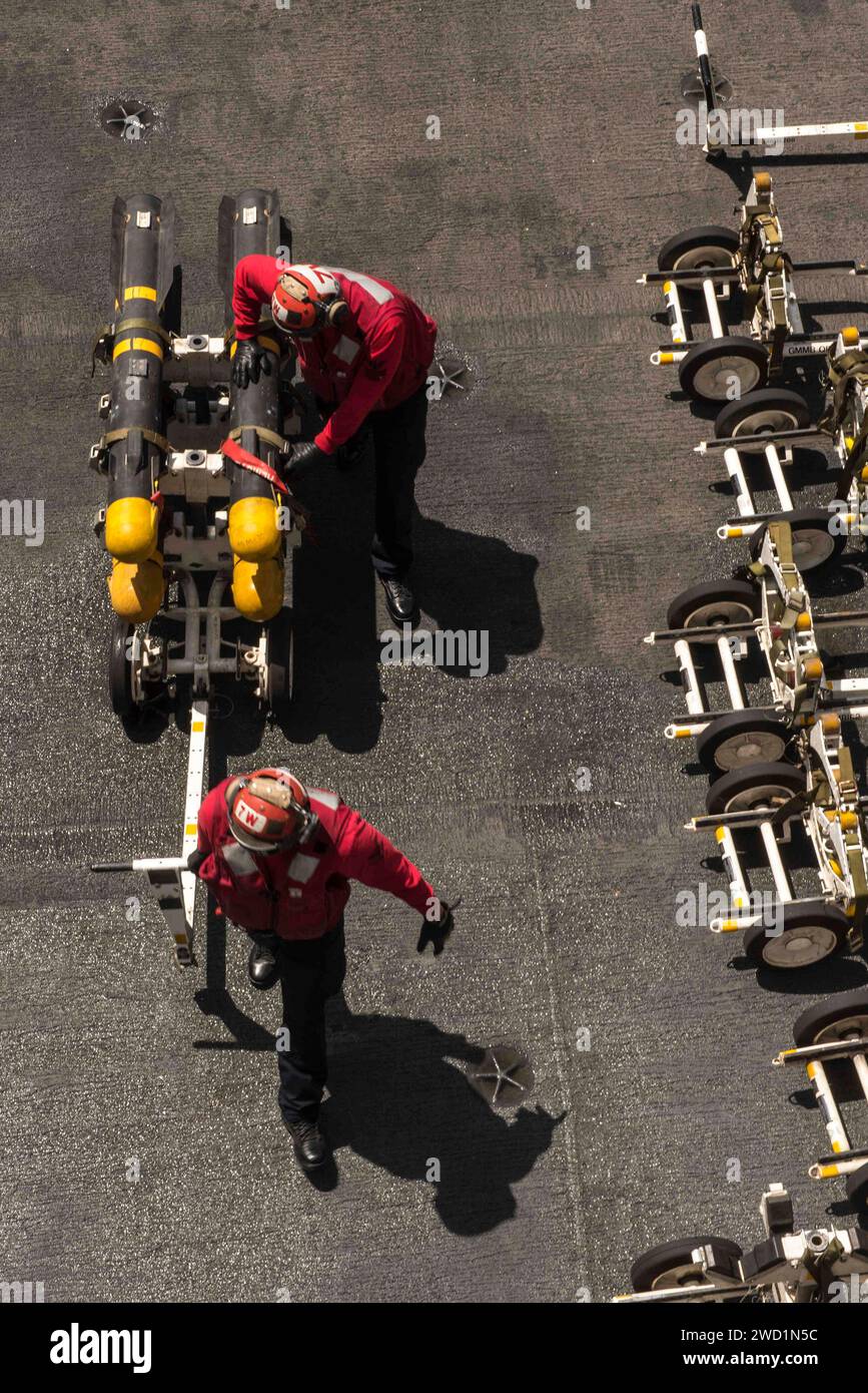 Sailors transport ordnance on the flight deck of the aircraft carrier USS George H.W. Bush. Stock Photo