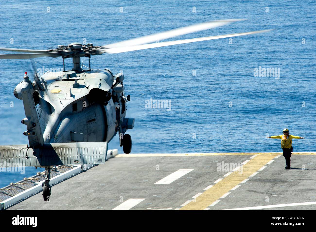 Aviation Boatswain's Mate guides an SH-60 Seahawk as it lands on the flight deck of USS America. Stock Photo
