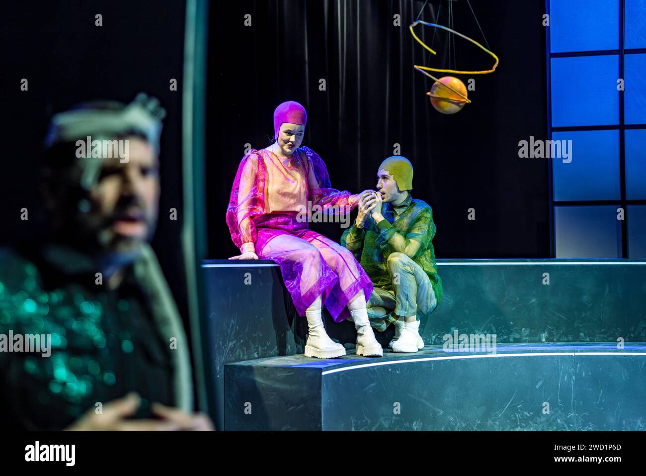17 January 2024, Brandenburg, Cottbus: Actors Gunnar Golkowski (Puck, l-r), Paula Aschmann (Hermia) and Torben Appel (Lysander) stand on stage during a photo rehearsal for the play 'Rose and Rain, Sword and Wound'. Director Friederike Drews premieres a concentrated version of Shakespeare's 'A Midsummer Night's Dream' at the Cottbus Kammerbühne. Ev Benzing's stage design transforms the plot away from earthly crises and catastrophes and into the saving universe. Beat Fäh's 1989 Shakespeare adaptation ROSE AND RAIN, SWORD AND WOUND is based on Erich Fried's translation of 'A Midsummer Night's Dre Stock Photo