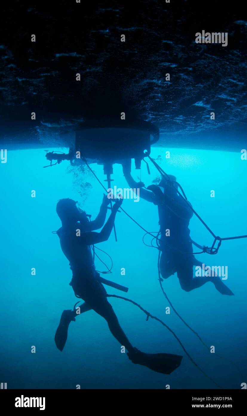 U.S. Navy divers conduct a ship's husbandry dive on USS Hue City. Stock Photo