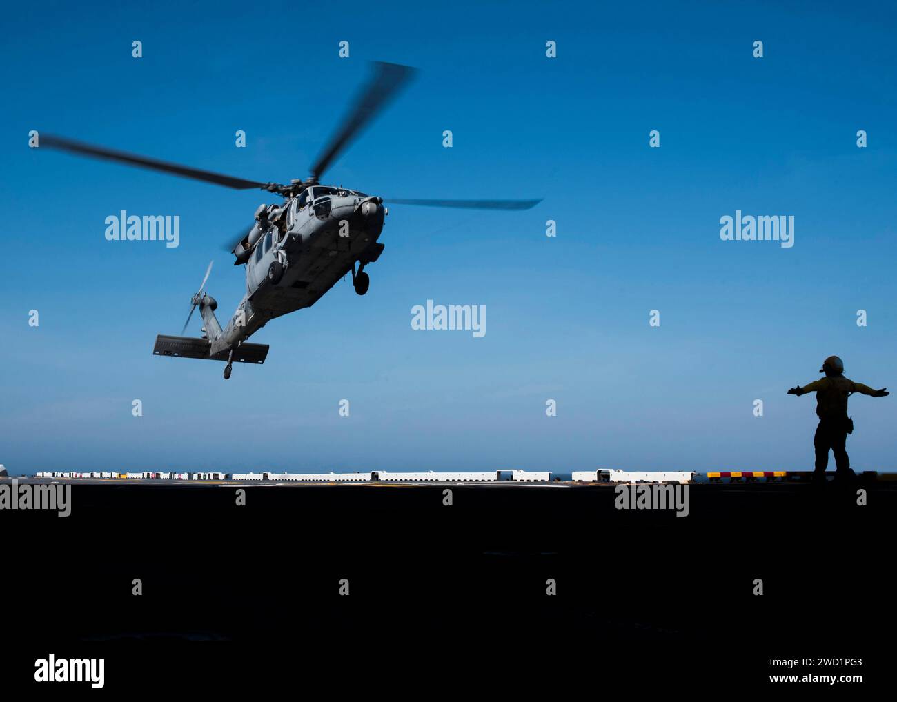 Aviation Boatswain's Mate signals an MH60S Sea Hawk helicopter on the flight deck aboard USS