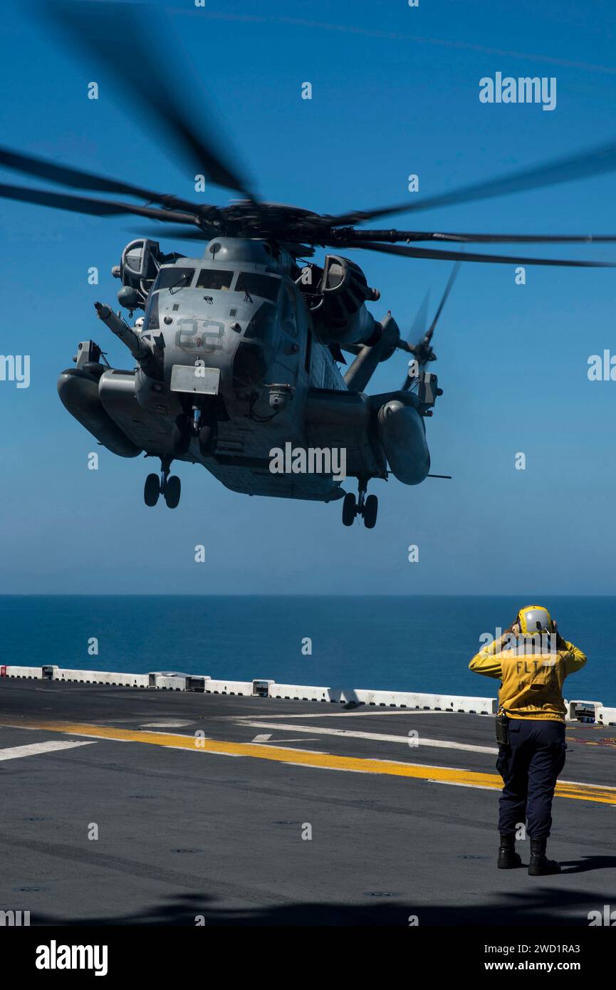 Aviation Boatswain's Mate signals a CH53E Super Stallion to land on the flight deck of USS