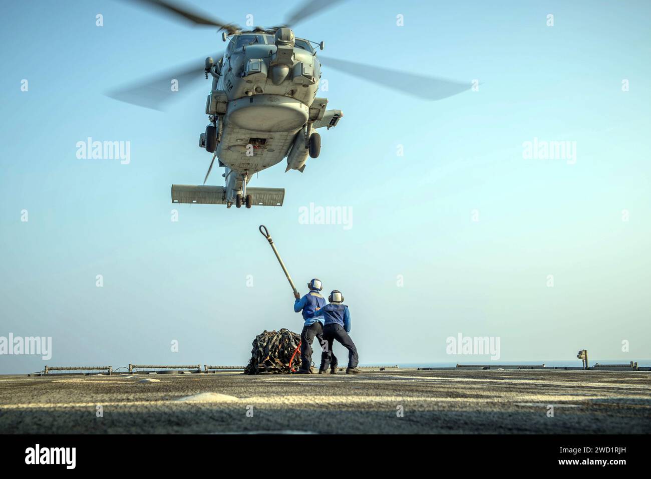 Seamen prepare to attach a pendant to an MH-60R Sea Hawk helicopter during vertical replenishment training. Stock Photo