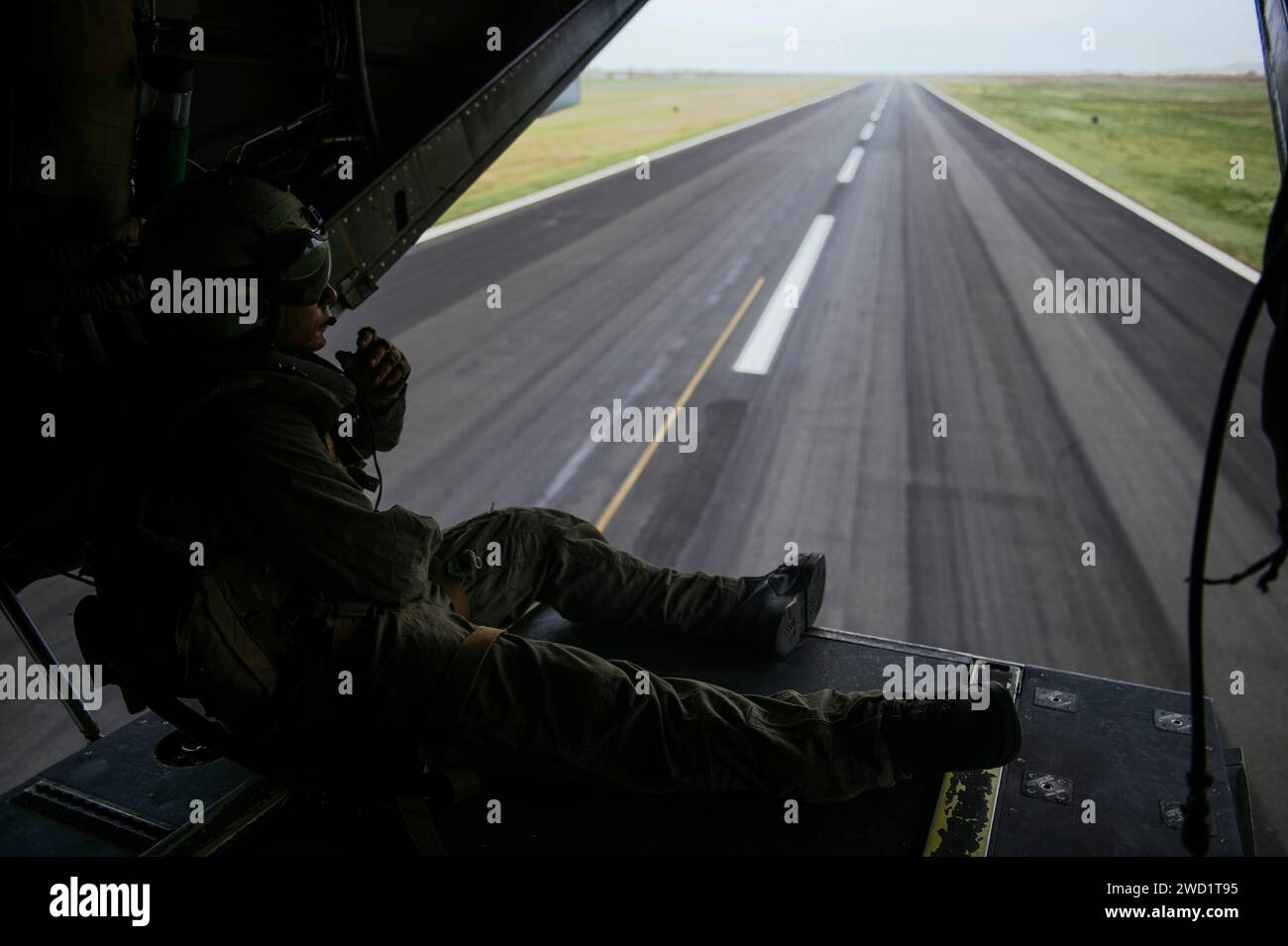 An MV-22 Osprey aircrewman relays information to pilots while transporting personnel. Stock Photo
