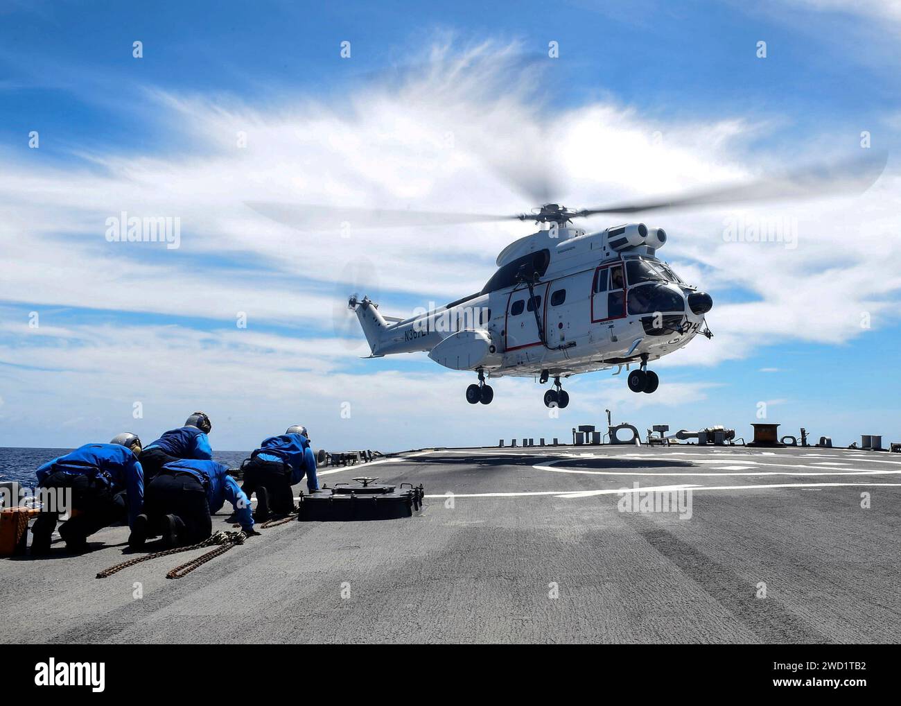 Sailors take cover as an SA-330J Puma helicopter lands on the flight deck of USS Benfold. Stock Photo