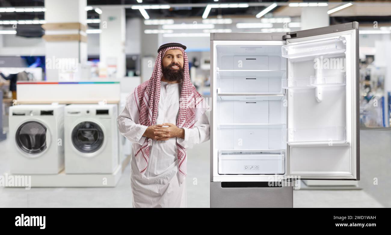 Saudi arab man leaning on a fridge inside a store Stock Photo