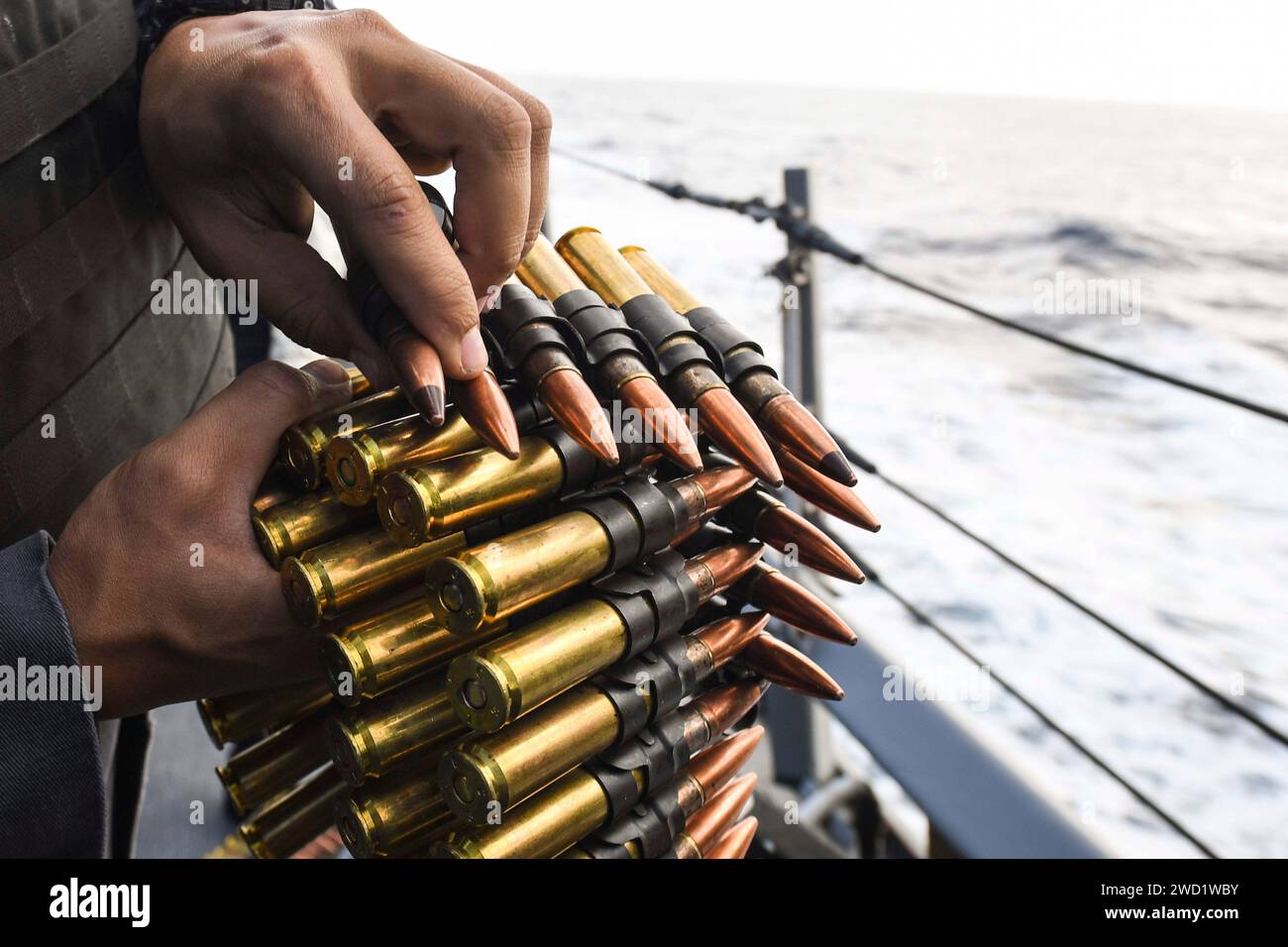 A Sailor handles ammunition for a .50 caliber machine gun. Stock Photo