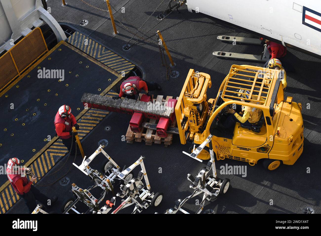Sailors load a forklift on the flight deck of the aircraft carrier USS Theodore Roosevelt. Stock Photo
